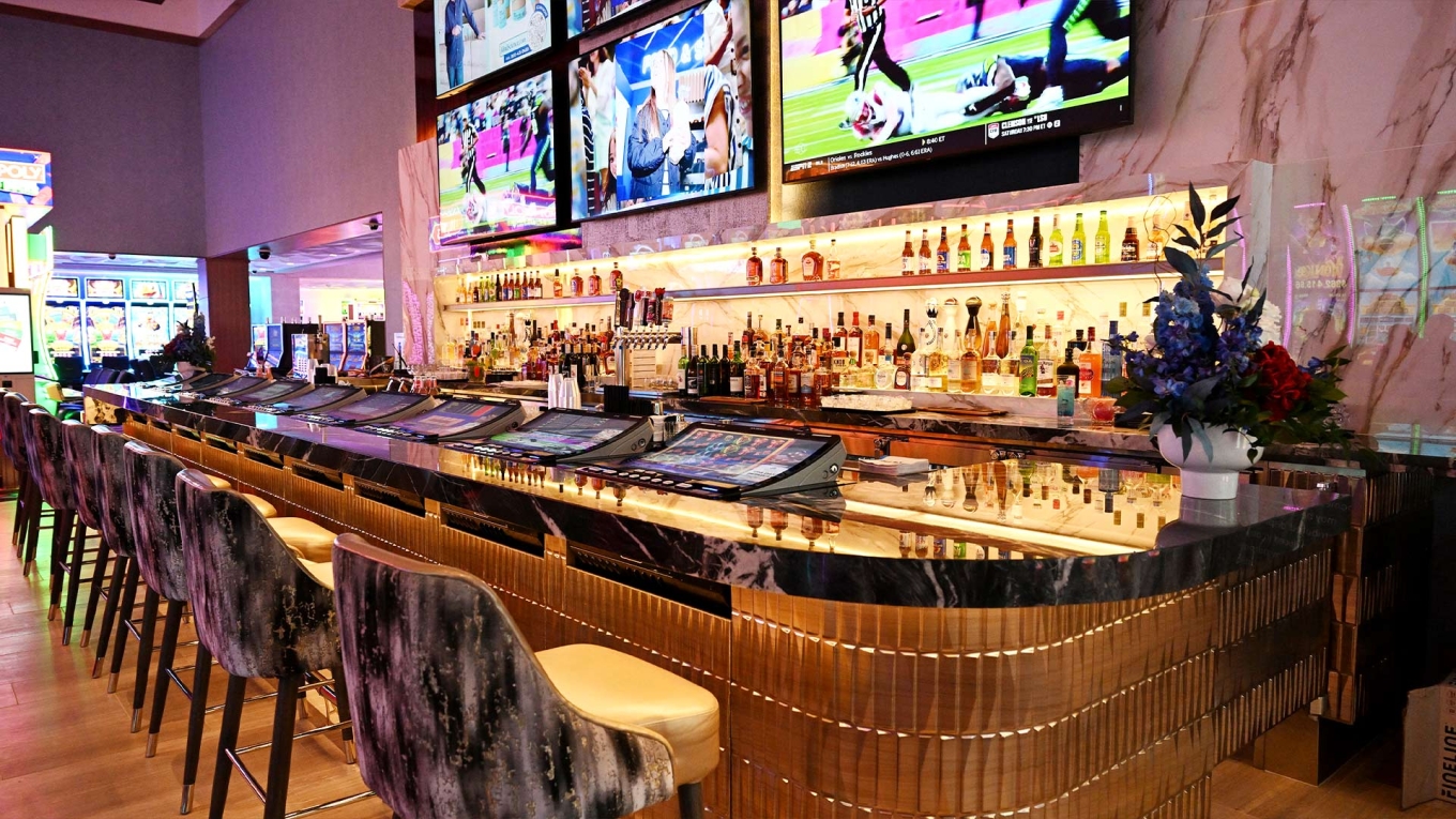 North Bar at Palms Resort & Casino, featuring a marble and gold bar top with built-in gaming terminals, patterned barstools, and a full liquor display beneath mounted sports screens.